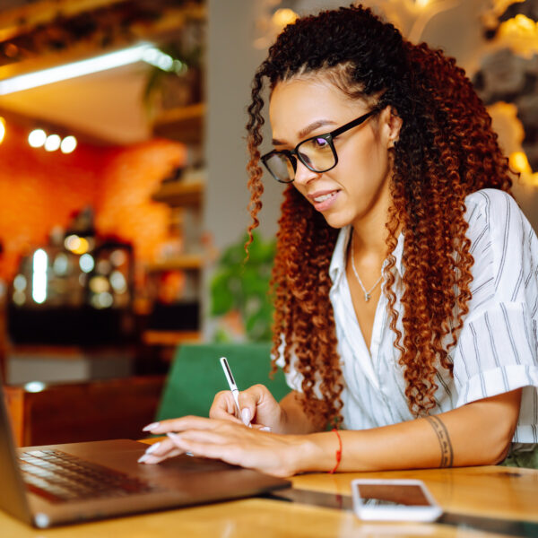 Portrait of African American woman sitting at cafe having video call on laptop computer.